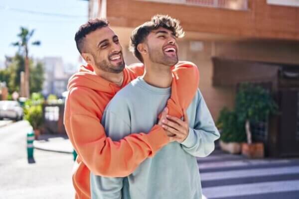 Two man couple hugging each other standing at street